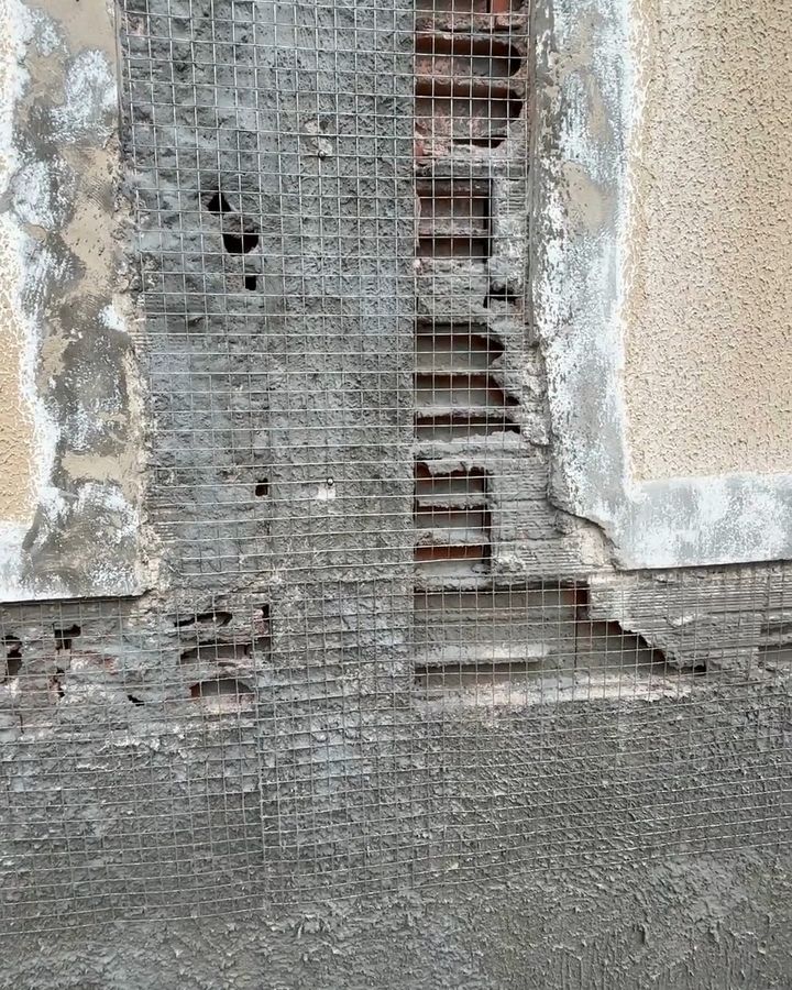 Fachada com revestimento argamassado removido, expondo tela metálica e alvenaria