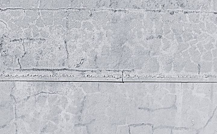 Superfície de parede com fissuras ramificadas no revestimento e na pintura